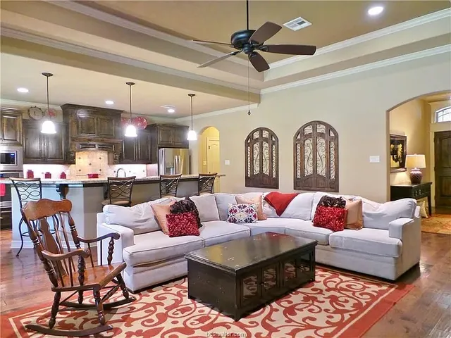 a living room with furniture kitchen view and a chandelier