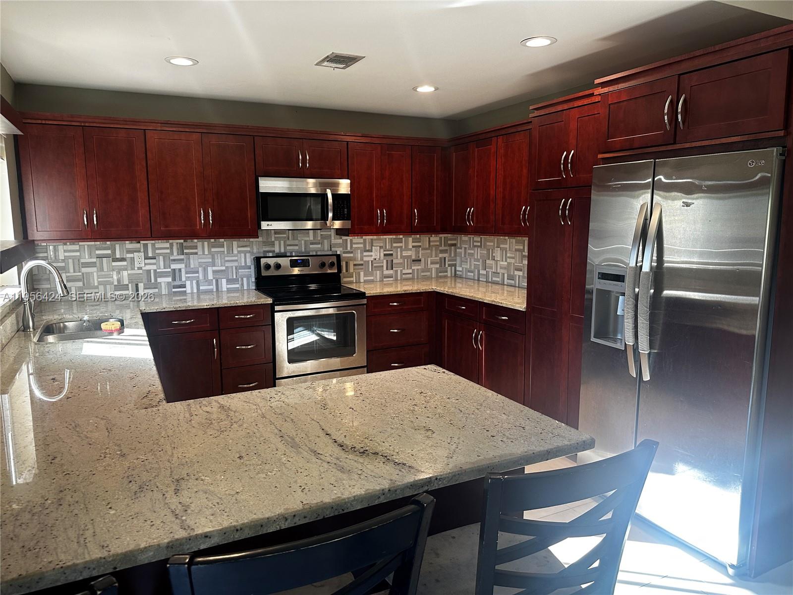 4249 Southwest 154th Avenue Miami, FL 33185 - Photo 6 of 24 a kitchen with stainless steel appliances wooden cabinets a center island and a refrigerator