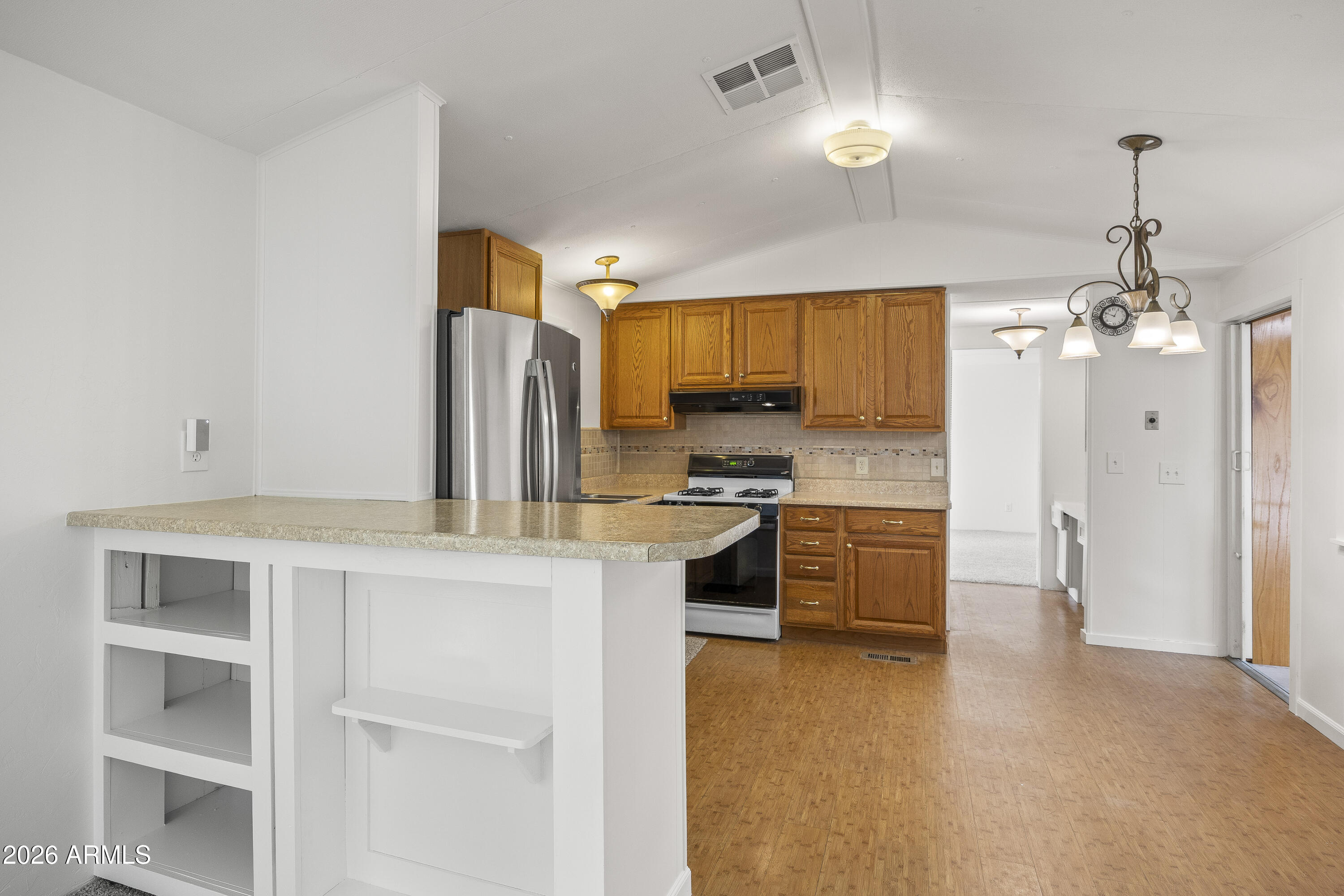 15940 North Goetz Place Tucson, AZ 85739 - Photo 16 of 37 a kitchen with kitchen island granite countertop wooden cabinets and refrigerator