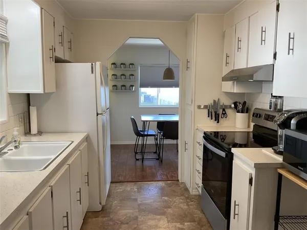 a kitchen with stainless steel appliances a sink a stove a refrigerator cabinets and a dining table