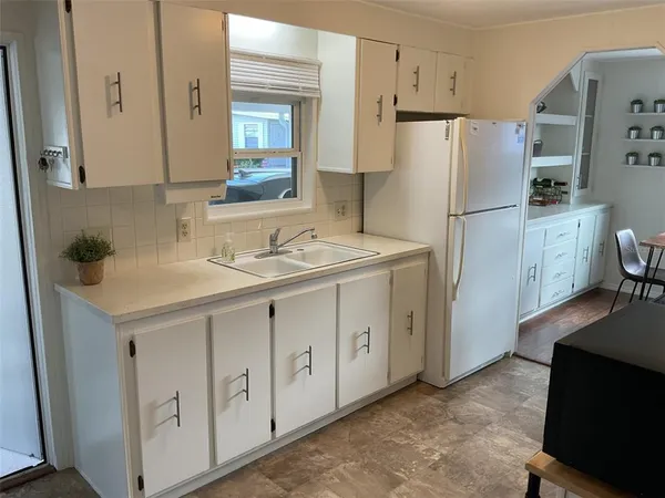 a kitchen with white cabinets and refrigerator