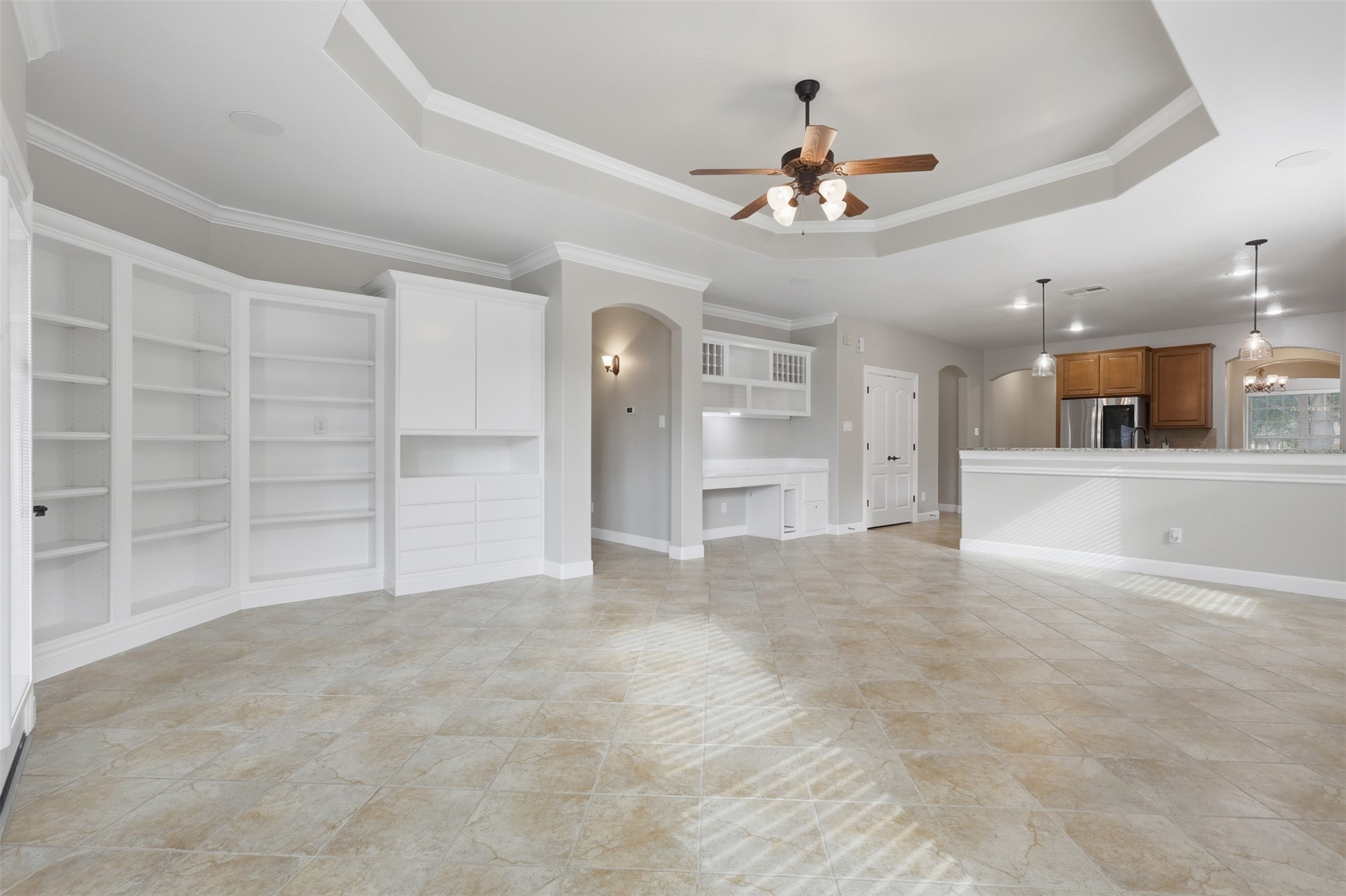 721 Rufina Street League City, TX 77573 - Photo 11 of 33 The expansive family room offers abundant space for relaxing or entertaining. Custom built-in cabinetry, open shelving, and an integrated workspace add both character and functionality, while the open-concept layout keeps the kitchen & living spaces beautifully connected.