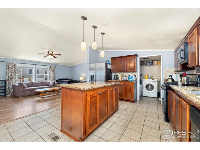 a large kitchen with stainless steel appliances granite countertop a stove a sink dishwasher and a refrigerator with wooden floor