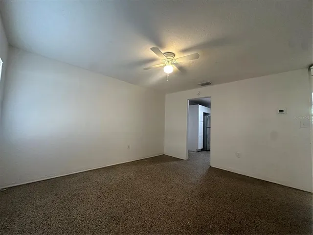 an empty room with a ceiling fan and a window