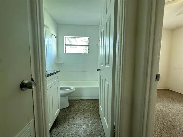 a bathroom with a granite countertop toilet a sink and a mirror