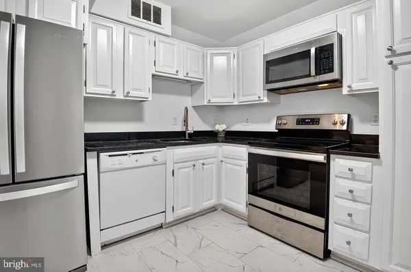 a kitchen with white cabinets stainless steel appliances and sink