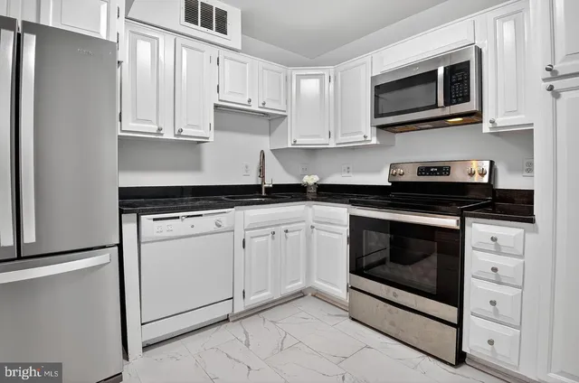 a kitchen with white cabinets stainless steel appliances and sink