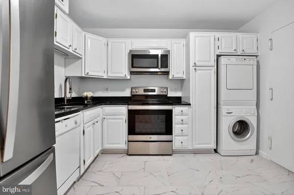 a kitchen with granite countertop a stove top oven and cabinets
