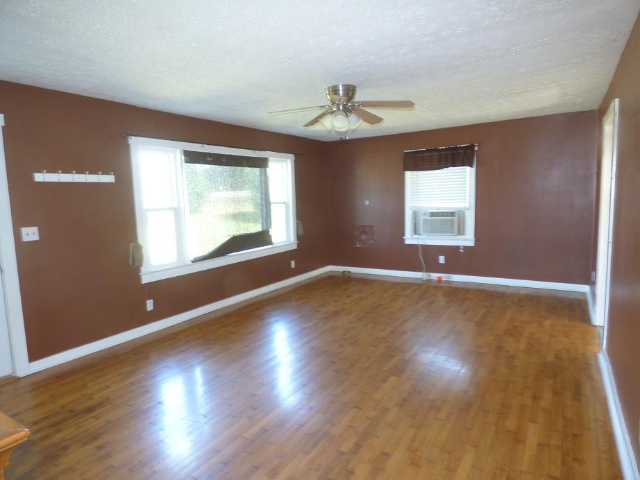 1259 1st Avenue Mount Pleasant, TN 38474 - Photo 4 of 18 an empty room with wooden floor chandelier fan and windows