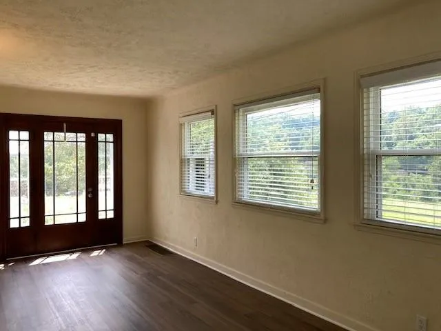 a view of an empty room with wooden floor and a window