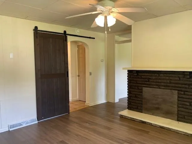 an empty room with wooden floor fan and windows