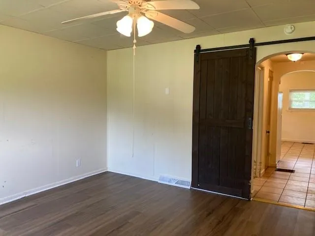 an empty room with wooden floor fan and windows