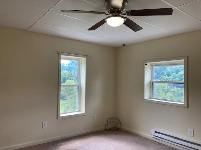 an empty room with windows and fan