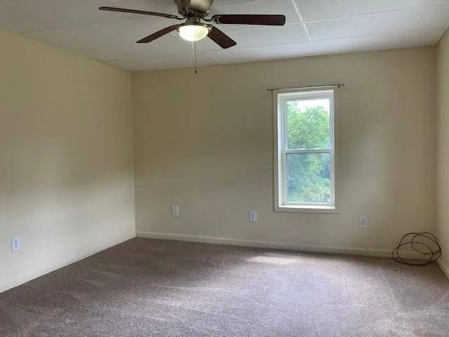an empty room with a window and a fan