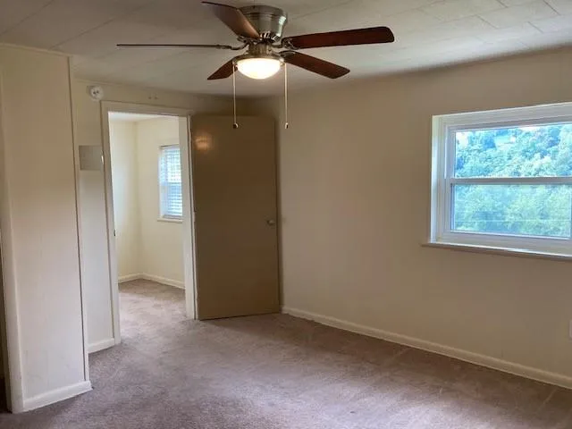 an empty room with windows and fan