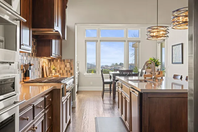 a kitchen with stainless steel appliances granite countertop a stove a sink and a refrigerator with wooden floor