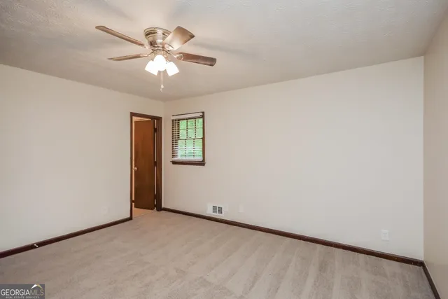 an empty room with a chandelier fan and windows