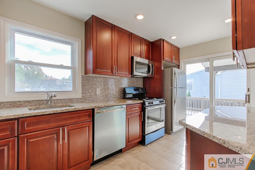 31 Longfield Road New Brunswick, NJ 08901 - Photo 1 of 15 a kitchen with stainless steel appliances granite countertop wooden cabinets a stove a sink and a large window
