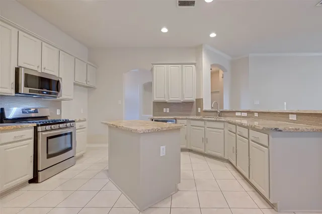 a kitchen with granite countertop a sink stove and cabinets