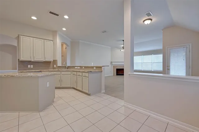 a kitchen with white cabinets and window