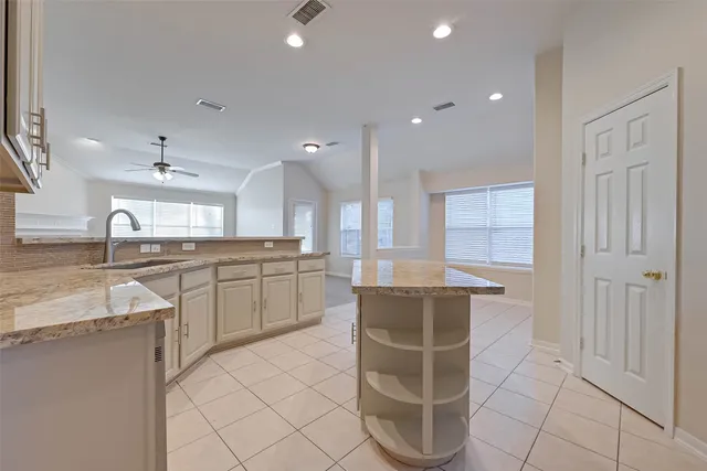a large kitchen with kitchen island granite countertop a sink and cabinets