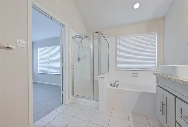 a spacious bathroom with a granite countertop sink a mirror and a bathtub