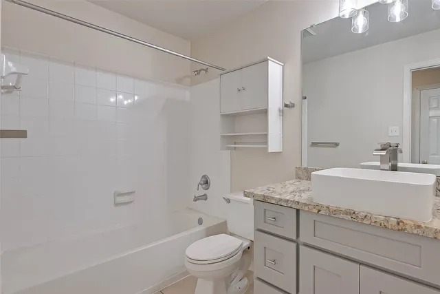 a bathroom with a granite countertop sink a toilet and a bathtub