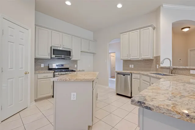 a kitchen with granite countertop a sink stove and refrigerator