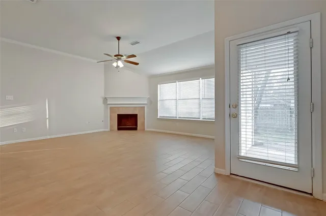 an empty room with chandelier fan and windows