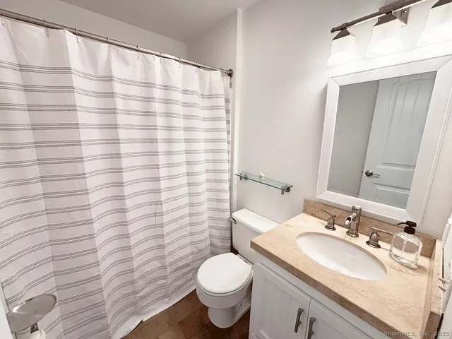 a bathroom with a granite countertop toilet sink and mirror