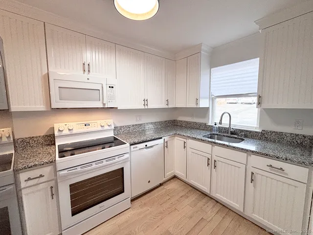 a kitchen with granite countertop white cabinets and white appliances