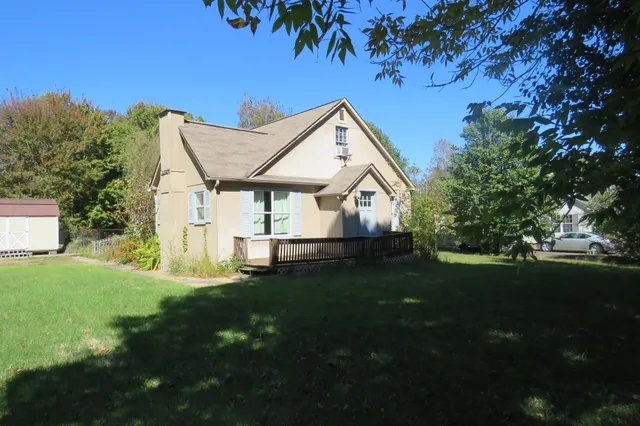 a view of a house with a big yard plants and large trees