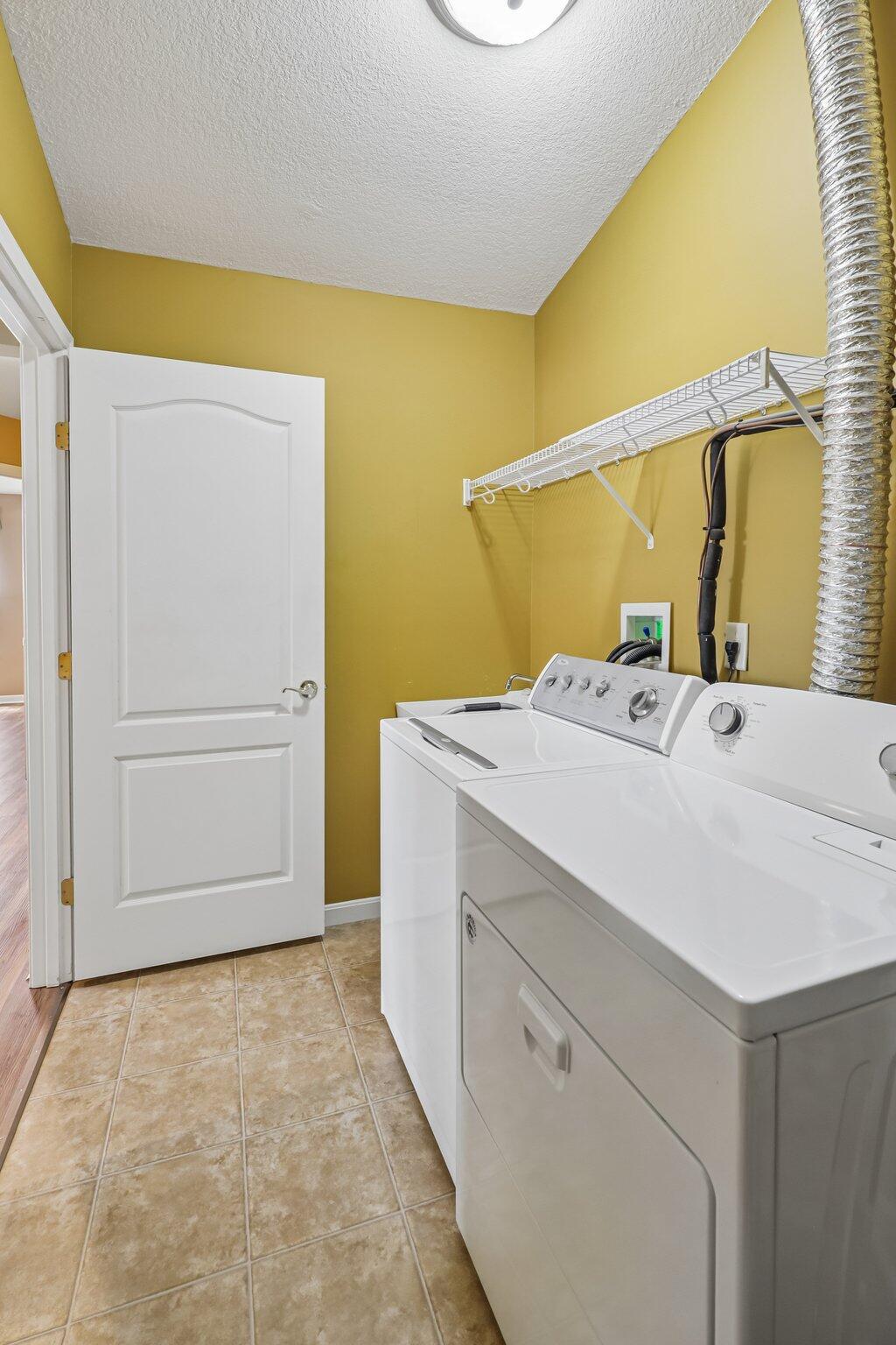 876 Flint Ridge Newport, KY 41076 - Photo 38 of 43 Dedicated laundry space featuring a white washer and dryer, tile flooring, and a wall-mounted wire shelving unit