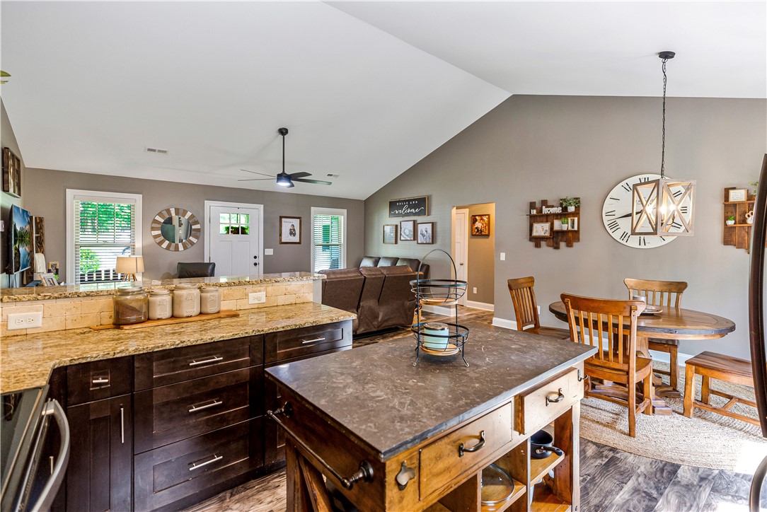 842 Conneross Road Townville, SC 29689 - Photo 14 of 34 A well-lit kitchen with granite countertops and rich cabinetry seamlessly transitions into a spacious living area.