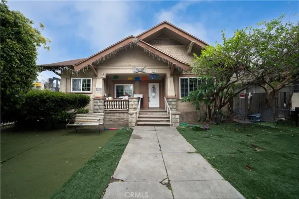 a front view of a house with a garden and trees