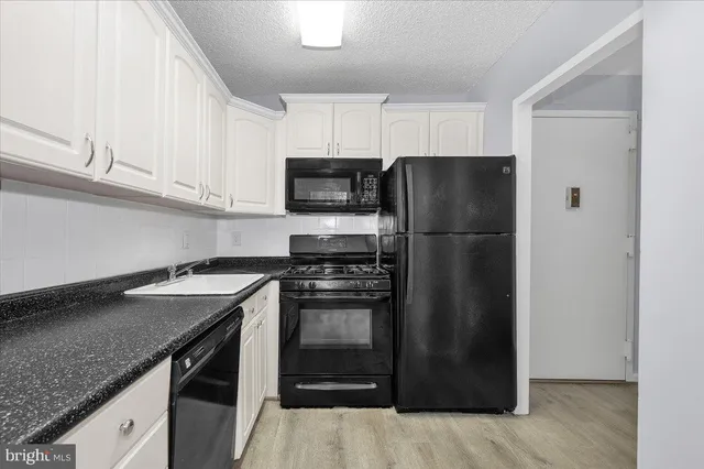 a kitchen with stainless steel appliances granite countertop a refrigerator a stove a sink and a microwave