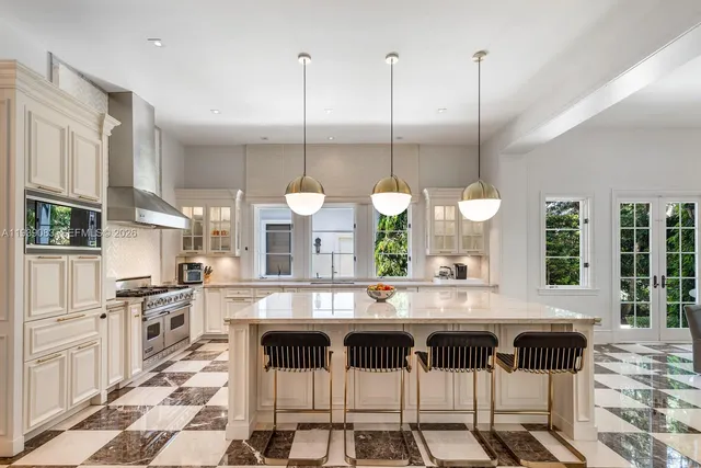a kitchen with stainless steel appliances kitchen island granite countertop a stove a sink and a white cabinets