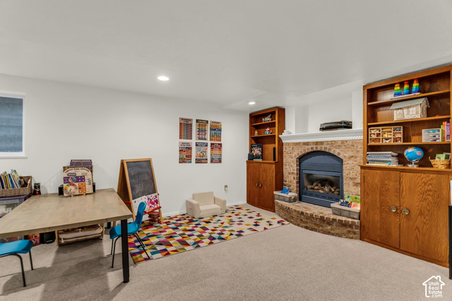 1073 Pineridge Road Sandy, UT 84094 - Photo 23 of 31 Recessed lighting, light-toned carpet, a gas fireplace with a brick surround, and built-in wood cabinetry