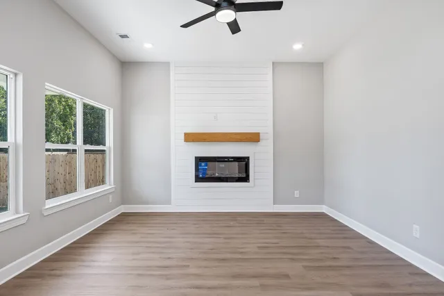 a view of an empty room with a window and wooden floor