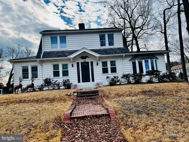 a front view of a house with a yard outdoor seating and covered with trees