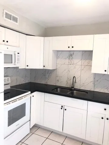 a kitchen with granite countertop white cabinets and white appliances