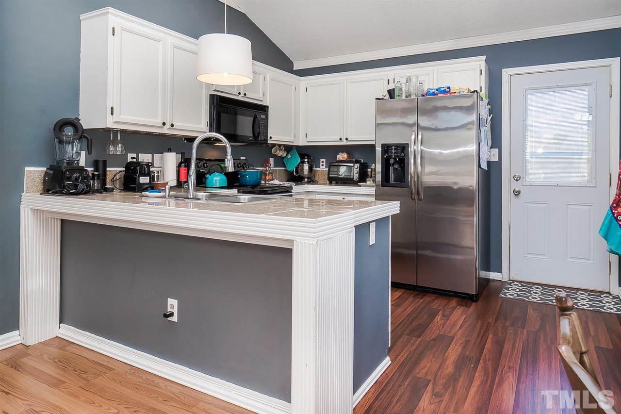 4125 Cobble Court Raleigh, NC 27616 - Photo 5 of 13 a kitchen with stainless steel appliances granite countertop a refrigerator a stove top oven a sink and dishwasher with wooden floor