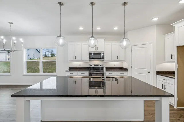 a kitchen with kitchen island a stove a sink a center island and windows
