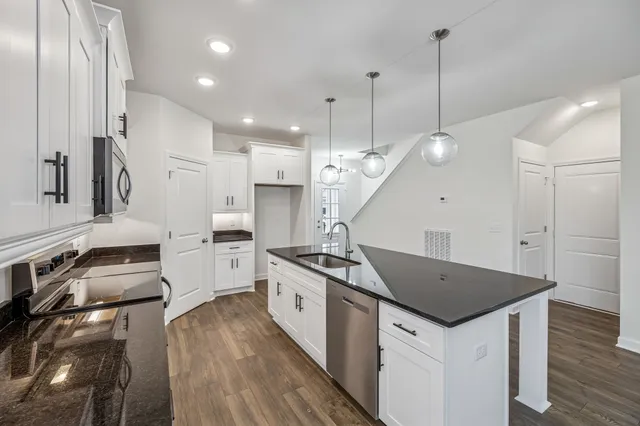 a kitchen with stainless steel appliances granite countertop a sink a stove and a wooden floors