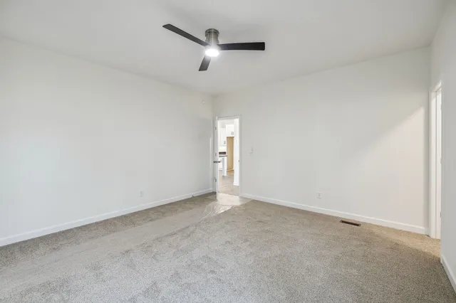 an empty room with a ceiling fan and window