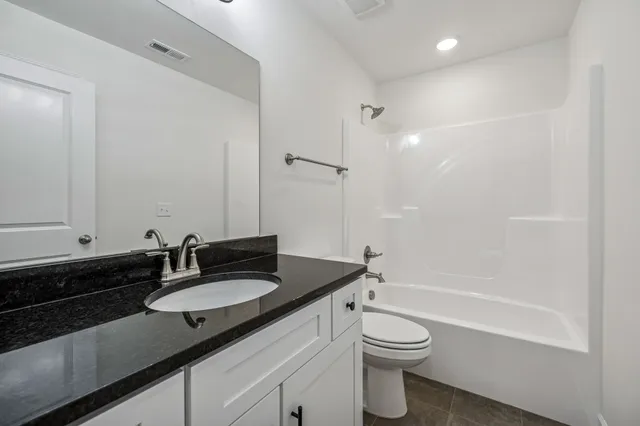 a bathroom with a granite countertop sink toilet a shower and a mirror