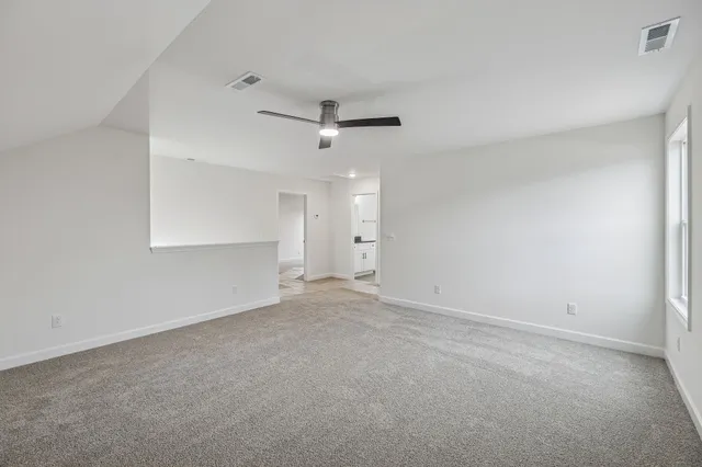 an empty room with a ceiling fan and a window