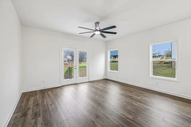 a view of an empty room with window and wooden floor