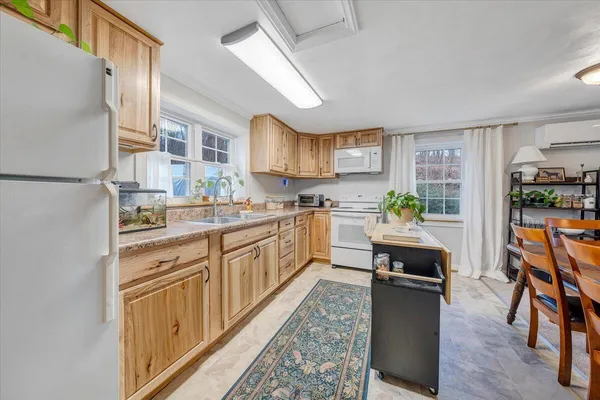 a kitchen with stainless steel appliances granite countertop a refrigerator a sink dishwasher a stove and white countertops with wooden floor