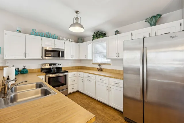 a living room with stainless steel appliances granite countertop furniture and a wooden floor